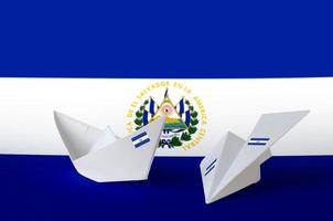 el salvador flagge auf papier origami flugzeug und boot dargestellt. handgemachtes kunstkonzept foto