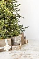 schöne geschenkboxen auf dem boden neben dem weihnachtsbaum im zimmer. weihnachts- und neujahrskonzept foto