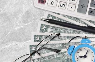 2 US-Dollar-Scheine und Taschenrechner mit Brille und Stift. Konzept für Geschäftsdarlehen oder Steuerzahlungssaison. Zeit, Steuern zu zahlen foto