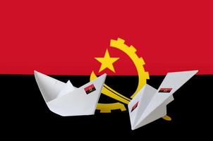 Angola-Flagge auf Papier Origami-Flugzeug und Boot dargestellt. handgemachtes kunstkonzept foto