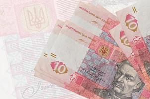 10 ukrainische Griwna-Scheine liegen im Stapel auf dem Hintergrund einer großen halbtransparenten Banknote. abstrakte Darstellung der Landeswährung foto