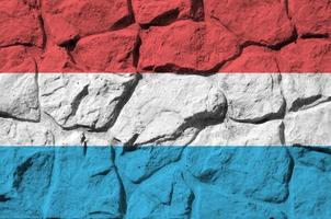 luxemburgische flagge in lackfarben auf alter steinmauer in der nähe dargestellt. strukturiertes banner auf felswandhintergrund foto