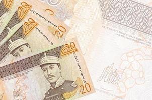 20 dominikanische Peso-Scheine liegen im Stapel auf dem Hintergrund einer großen halbtransparenten Banknote. abstrakter betriebswirtschaftlicher hintergrund foto