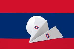 Laos-Flagge auf Papier-Origami-Flugzeug abgebildet. handgemachtes kunstkonzept foto