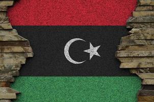 Libyen-Flagge in Lackfarben auf der alten Steinmauer in der Nähe dargestellt. strukturiertes banner auf felswandhintergrund foto