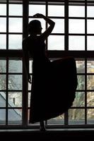 Silhouette einer Frau mit gebeugtem Bein vor dem Fenster foto