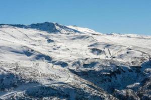 Panoramablick auf das Skigebiet in Sierra Nevada, Skifahrer entlang der Pisten foto