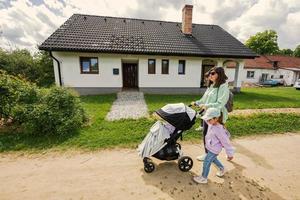 mutter mit kinderwagen und kindern, die im dorf spazieren gehen. foto