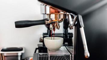 Kaffeeextraktion aus der Kaffeemaschine mit einem Siebträger, der Kaffee in eine Tasse gießt, Espresso aus der Kaffeemaschine im Café foto