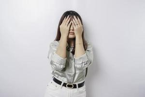 ein porträt einer asiatischen frau, die ein salbeigrünes hemd trägt, das durch weißen hintergrund isoliert ist, sieht deprimiert aus foto