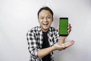 Ein Porträt eines glücklichen asiatischen Mannes lächelt, während er auf seinem Telefon Platz für Kopien zeigt, isoliert durch weißen Hintergrund foto