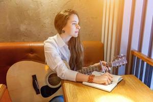 junges Mädchen, das im Café Gitarre spielt foto