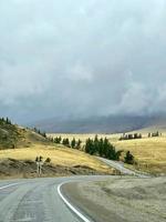 die kurvenreiche straße zwischen den hügeln in den bergen, ein teil des tschuisky-trakts, altai, russland foto