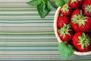 Reife süße Erdbeeren in Weidenkorb und Minzblättern. foto