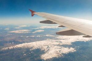 Blick aus dem Fenster des Flugzeugs, das über die Berge fliegt foto