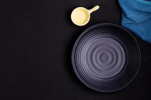 leere schwarze runde platte mit probetuch auf dem tisch auf einem dunklen, stimmungsvollen schwarzen hintergrund. einfaches abendessen mit kopierraum, draufsicht foto