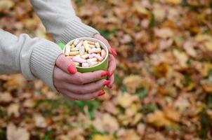 Frau mit weißem Pullover, die eine grüne Kaffeetasse hält foto