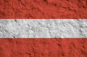 österreich-flagge in hellen farben auf alter reliefputzwand dargestellt. strukturierte Fahne auf rauem Hintergrund foto