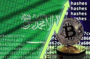 saudi-arabien-flagge und steigender grüner pfeil auf dem bitcoin-mining-bildschirm und zwei physische goldene bitcoins foto