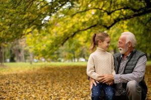 Großvater verbringt am Herbsttag Zeit mit seiner Enkelin im Park foto