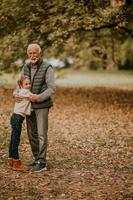 Großvater verbringt am Herbsttag Zeit mit seiner Enkelin im Park foto