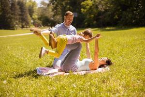 glückliche junge Familie mit süßer kleiner Tochter, die an einem sonnigen Tag Spaß im Park hat foto