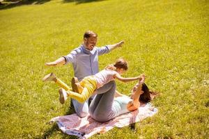 glückliche junge Familie mit süßer kleiner Tochter, die an einem sonnigen Tag Spaß im Park hat foto