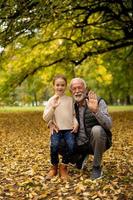 Großvater verbringt am Herbsttag Zeit mit seiner Enkelin im Park foto