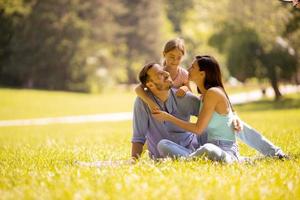 glückliche junge Familie mit süßer kleiner Tochter, die an einem sonnigen Tag Spaß im Park hat foto