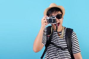 Fröhliche asiatische Rucksacktouristen, die reisen, um im Studio Fotos auf blauem Hintergrund zu machen.