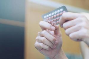 Frauenhände öffnen Antibabypillen in der Hand. Verhütungspille essen. foto