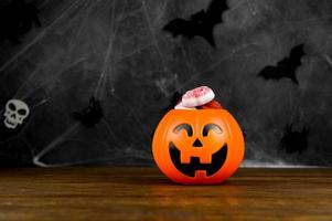 halloween-banner mit trick or treat concept.jack'o'lantern geformte bonbonschale mit delicios gruseligen süßigkeiten auf dunklem hintergrund mit spinnennetz foto