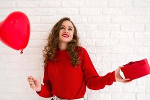 glückliche junge frau, die geschenk und ballon hält. frauen- oder valentinstagkonzept. foto