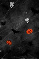schwarze fliegende fledermäuse, spinnen, schädel und kürbisse im web über dunklem betonhintergrund. vertikales banner foto
