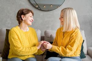 glückliche erwachsene tochter, die mit ihrer mutter kommuniziert und zusammen auf dem sofa sitzt. foto