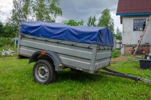 der Anhänger für das Auto ist mit einer Markise geschlossen. Transport von Sachen. foto