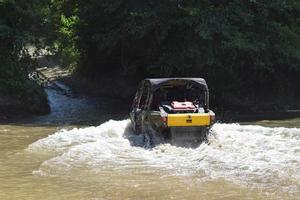 der mann auf dem atv überquert einen bach foto