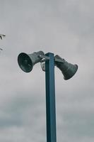 Hohe Säule mit zwei Lautsprechern gegen bewölkten Himmel. foto