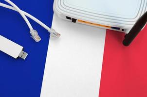 frankreich-flagge auf tisch mit internet-rj45-kabel, drahtlosem usb-wlan-adapter und router. Konzept der Internetverbindung foto