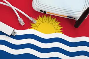 kiribati-flagge auf dem tisch mit internet-rj45-kabel, drahtlosem usb-wlan-adapter und router. Konzept der Internetverbindung foto