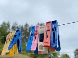 Bunte Wäscheklammern im Freien, auf dem Seil über Unschärfehintergrund foto