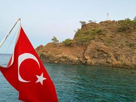 Türkische Flagge auf Schiff im Meer mit Strandpromenade im Hintergrund, Istanbul, Türkei foto