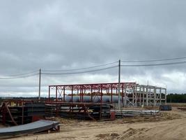 Hubarbeitsbühne bei der Arbeit innerhalb der Metallstruktur eines großen im Bau befindlichen Industriegebäudes foto