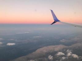 fliegen und reisen, blick aus dem flugzeugfenster auf den flügel bei sonnenuntergang foto