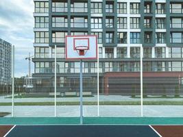 Outdoor-Sportarten. Basketballplatz in einem Wohngebiet. Ballspiel neben hohen Glashäusern. Basketballkorb auf dem Platz. strapazierfähiges Anti-Rutsch-Gummi zum Laufen foto