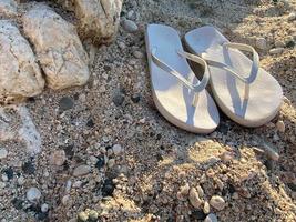 Flip-Flops auf hellem Sand. Textur von hellem Sand. das konzept eines strandurlaubs. Sommerkonzept. flache Lage, Draufsicht, Kopierbereich foto