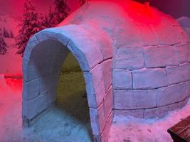 Iglu und Schneeschutz in hoher Schneeverwehung mit Berggipfeln im Hintergrund foto