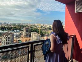 Bau einer neuen Wohnanlage im Stadtzentrum. Blick von oben auf die Baustelle. ein mädchen mit langen, dunklen haaren beobachtet auf dem balkon den hausbau foto