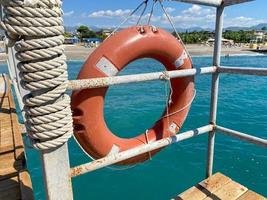 Runder, nicht sinkender roter Rettungsring zur Sicherheit, um das Leben von Ertrinkenden zu retten Touristen vor dem Hintergrund des Meeres in einem warmen östlichen tropischen Land Southern Paradise Resort foto