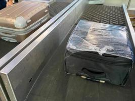 ein koffer liegt auf einem gepäckband in der ankunftshalle von flughafenpassagieren, das konzept der gepäckausgabe oder des verlustes foto